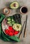 Hawaiian salmon poke bowl with seaweed, cucumber, avocado and sesame seeds. Vertical photo