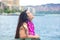 Hawaiian teen with lei sitting by ocean, Waikiki in background