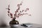 Hawthorn branches with red berries in vase and books on grey table indoors