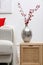 Hawthorn branches with red berries on wooden commode in living room