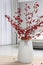 Hawthorn branches with red berries on wooden table in bedroom