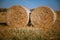 Hay bail harvesting in wonderful autumn farmers field landscape with hay stacks