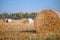 Hay bail harvesting in wonderful autumn farmers field landscape with hay stacks