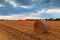 Hay bale in the field on a stormy evening with sun setting on the horizon