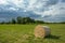 The hay bale lies on the meadow, rainy clouds