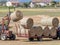 A hay bale is lifted with a tractor to be added to the others on a trailer