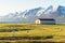 Hay bales and a barn in grassy field along the coast of a fjord in Iceland at sunset