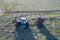 Hay harvesting. A single tractor with a baler in a pasture with swaths of cut grass. Drone footage.