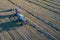 Hay production. Tractor in the pasture picks up swaths of cut grass, presses them and pulls out the finished bale. Drone footage.