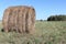 Hay roll lying on a sloping field in autumn