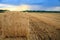 Hay-roll on meadow against sunset background