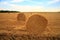 Hay-roll on meadow against sunset background