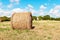 Hay roll on meadow with blue sky