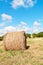 Hay roll on meadow with blue sky