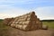 Hay storage in field near farm. Haystacks prepared for animal feed in winter. Stacks dry hay open air field storage. Store hay