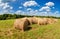 Hay and straw bales on farmland under blue sky