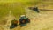 Haymaking on a hillside with rows of hay, a hay tedder and a hay-loader