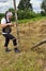 Haymaking season, two village women work in the field, preparing a wooden support for drying hay on it by driving it into the