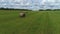 Haystack agriculture field landscape with pine trees growing in the distance against blue cloudy sky. Shot. Hay bales