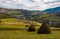 Haystacks on grassy meadow in autumn mountains