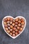 Hazelnut harvest. Nut in a heart plate on on black slate background.