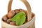 Hazelnut lies in a wooden basket on a white isolated background. Unpeeled hazelnuts in shell and green leaves