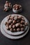 Hazelnuts in a ceramic plate . Lots of nuts on a dark background. Vertical photo. Food with a high protein concentrate. Natural