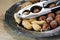 hazelnuts, peanuts and walnuts with a nutcracker on an old silver plate on rustic wood