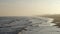 Hazy evening beach scene at the Gulf of Mexico with sand, waves, cars and people enjoying themselves as the sun sets