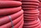 HDPE corrugated pipe texture background. Protection underground cable. Rolled up red corrugated PVC pipe. Red building pipes.