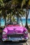 HDR Cuba pink american Oldtimer parked under palms near the beach in Varadero