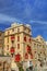 HDR photo of an old historic building with red balconies and windows and against a blue sky at Valletta, Malta