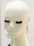 Head of a bald white female mannequin with false eyelashes and silver earrings