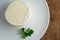 A head of brined cheese, feta, with a sprig of parsley