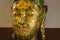 Head of a Buddha statue covered in gold leaf offering in Wat Phutthaisawan