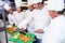 Head chef teaching his colleagues how to slice vegetables