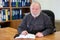 The head of a college or university faculty or department, elder Caucasian man sitting at the desk with notebook