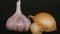 Head of garlic and two onions on a black background.
