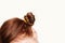 Head of a girl with two messy twisted curled red hair buns on white background. Creative hairstyle. Copyspace.