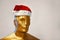 Head of golden figure of man in Santa Claus hat.