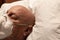 Head of a man wearing a respirator, asleep on hospital pillow, bald chemotherapy coronavirus, creative copy space