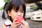 Head short of cute girl is biting at a red apple. Children eat fruit. Asian girl uses two hands to holding an apple.