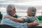 Head shot close up portrait happy grey haired middle aged woman snuggling to smiling older husband, enjoying sitting on bench at