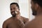 Head shot mirror reflection African American man using cleansing sponge