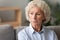 Head shot older woman lost in thoughts, sitting on couch