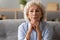 Head shot peaceful older woman dreaming alone, sitting on couch