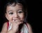 A head shot portrait of an adorable indian baby looking at the camera with selective focus on eyes with black background