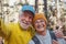 Head shot portrait close up of cute couple of old seniors taking a selfie together in the mountain forest looking at the camera
