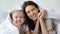 Head shot portrait happy mother and little daughter in bed