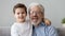 Head shot portrait little grandson embraces grey-haired elderly grandfather